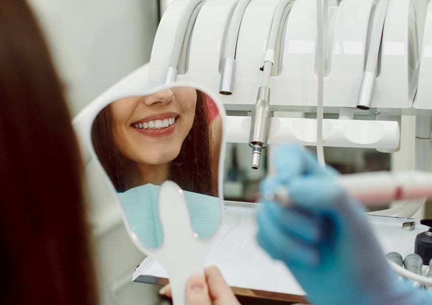 Patient checking her smile in a mirror after cosmetic dental treatment in Fort Wayne